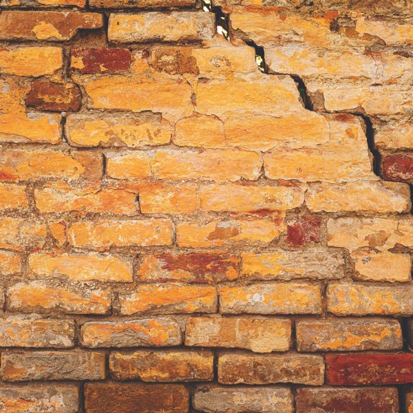Damaged cracked old brick wall structure, due to structural foundation failure and deterioration
